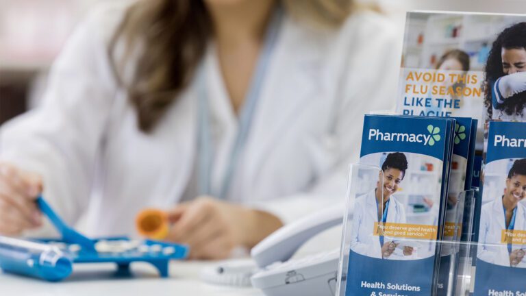 Pharmacy brochures with pharmacy professional working in the background.