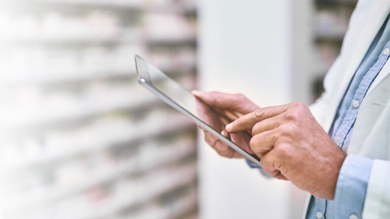 Closeup of pharmacy professional using tablet.