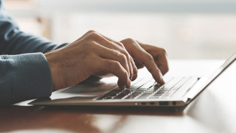 Closeup of hands typing on laptop